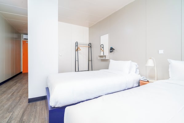 Habitación de hotel con dos camas, un armario, un espejo y una percha.