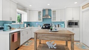 Uma cozinha moderna com armários brancos, uma mesa de madeira e uma decoração de peixe.