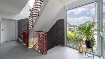 Ein modernes Interieur mit Treppe, großen Fenstern und einer Topfpflanze.