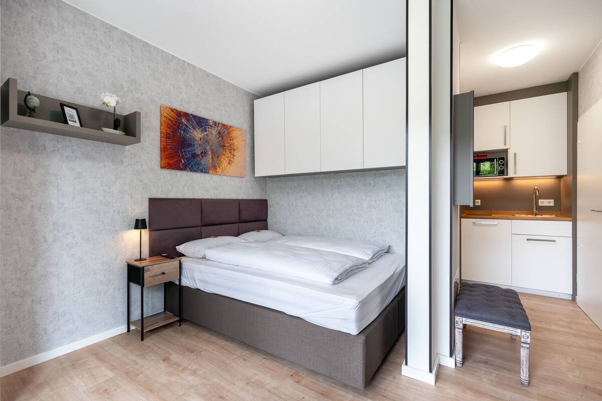 A modern bedroom with a bed, bedside table, and a small bench.