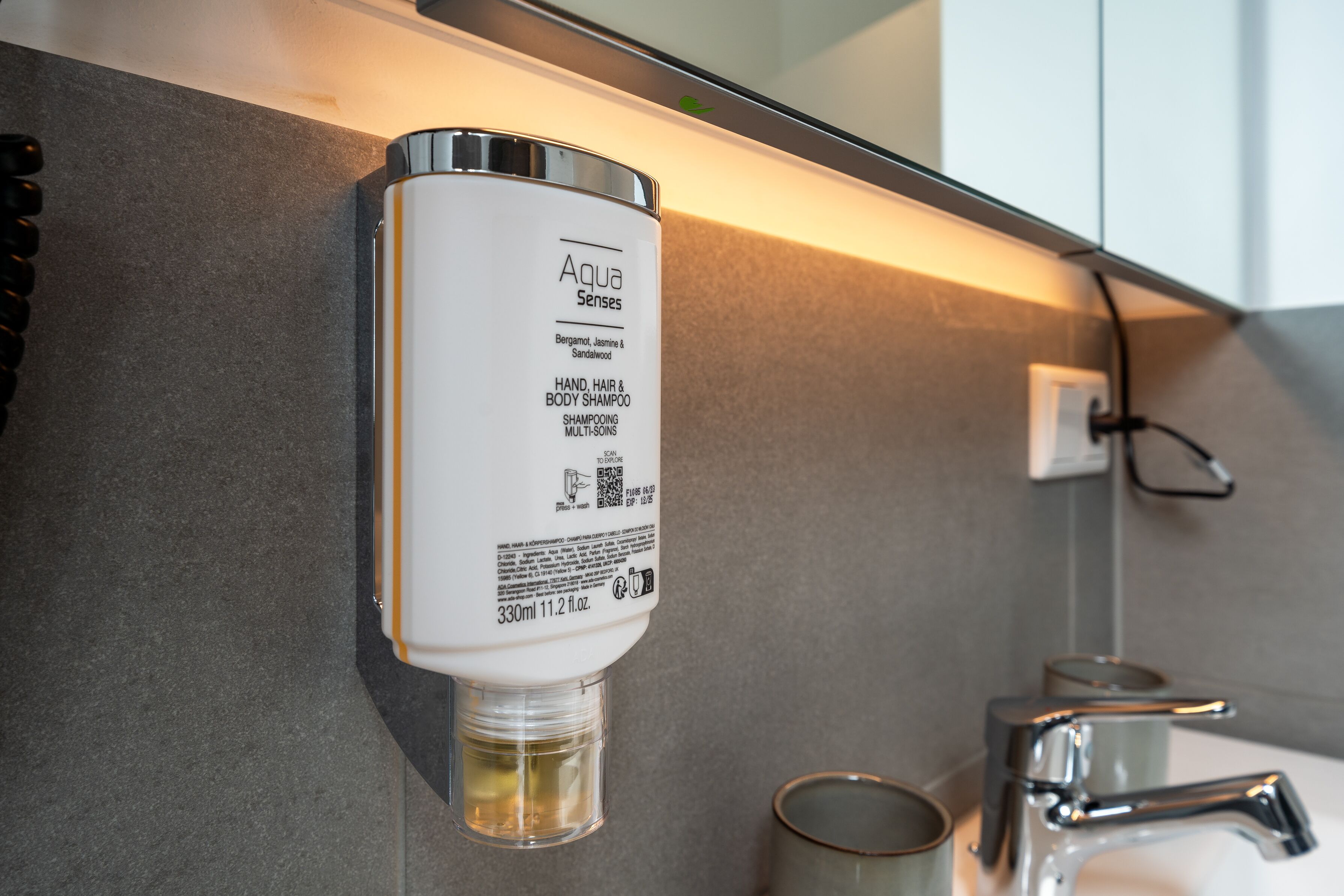 A hand sanitizer dispenser labeled "Aqua Senses" with Bergamot, Jasmine & Sandalwood scents, 330ml, 11.2 fl.oz.