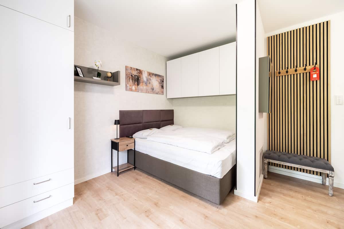 A modern bedroom with a bed, bedside table, and a bench against the wall.