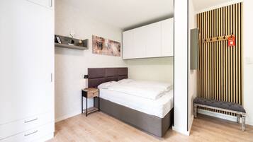 A modern bedroom with a bed, bedside table, and a bench against the wall.