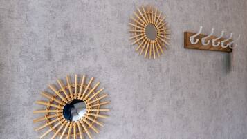 A wall with three wall-mounted items: a circular mirror with a wooden frame, a circular mirror with a wooden frame, and a wooden wall-mounted rack with hooks.