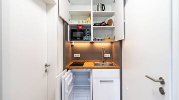 A compact kitchen with a built-in microwave, a sink, and a small refrigerator.