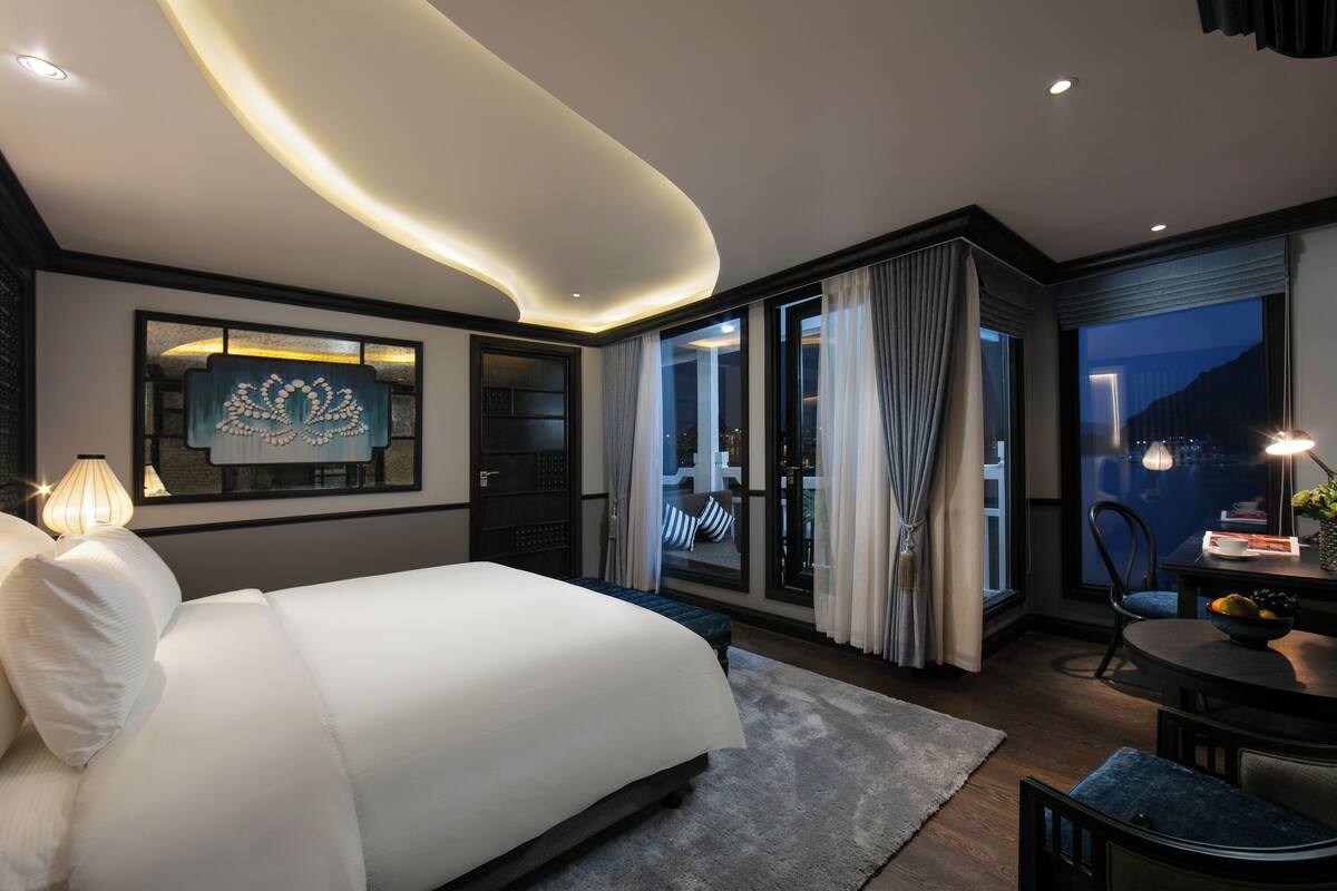 Une chambre d’hôtel moderne dotée d’un grand lit, d’un coin repas et d’un balcon avec des rideaux.