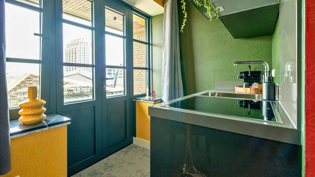 A compact kitchen with a built-in sink, a window with a view of buildings, and a small countertop with a decorative item.