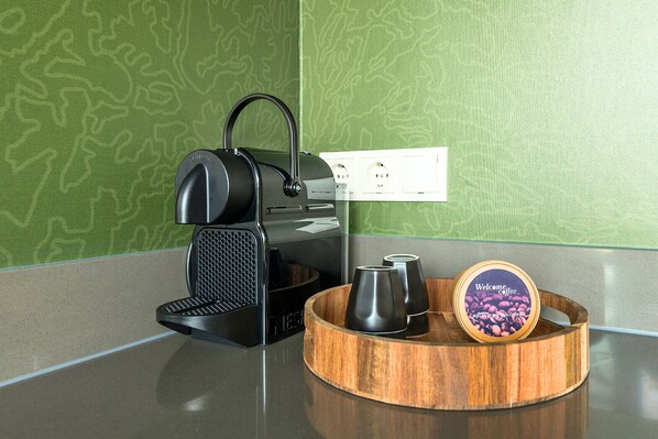 A coffee maker, a cup, and a welcome mug on a countertop.