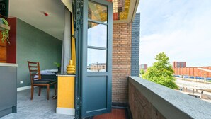 A balcony with a view of a train station and buildings.