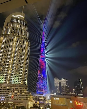 Un edificio de gran altura con un llamativo letrero de 'EMAAR' en la parte superior, que presenta un diseño arquitectónico moderno con fachada curva y varios balcones.