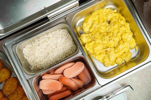 A buffet with rice, scrambled eggs, and sausages.