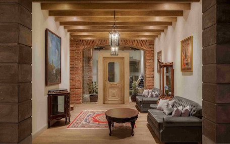 A spacious living room with a wooden ceiling, a large sofa, a coffee table, and a chandelier.