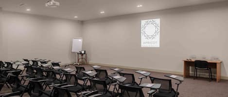 A conference room with rows of chairs, a projector screen, and a whiteboard.