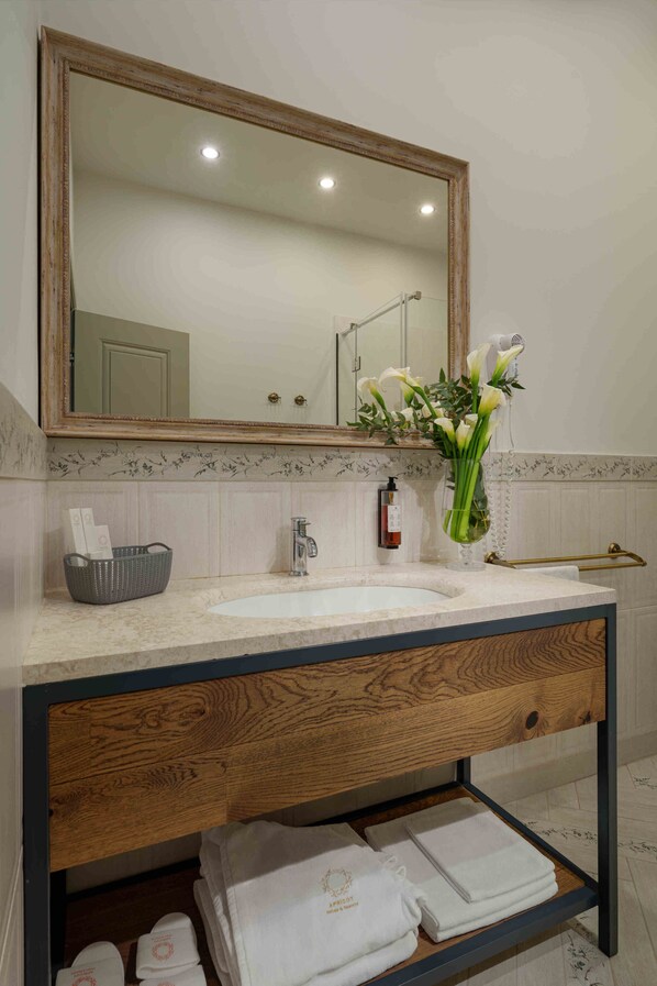 A bathroom with a wooden vanity, a large mirror, a sink, and a towel rack. - Grand Hotel Gyumri (Gyumri)