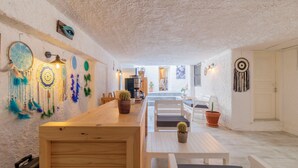 A cozy dining area with a wooden table and chairs, surrounded by white walls adorned with dreamcatchers and potted plants. - Das Hotel (Çesme)