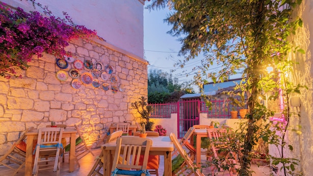 An outdoor patio with stone walls, wooden furniture, and decorative plates. - Das Hotel (Çesme)