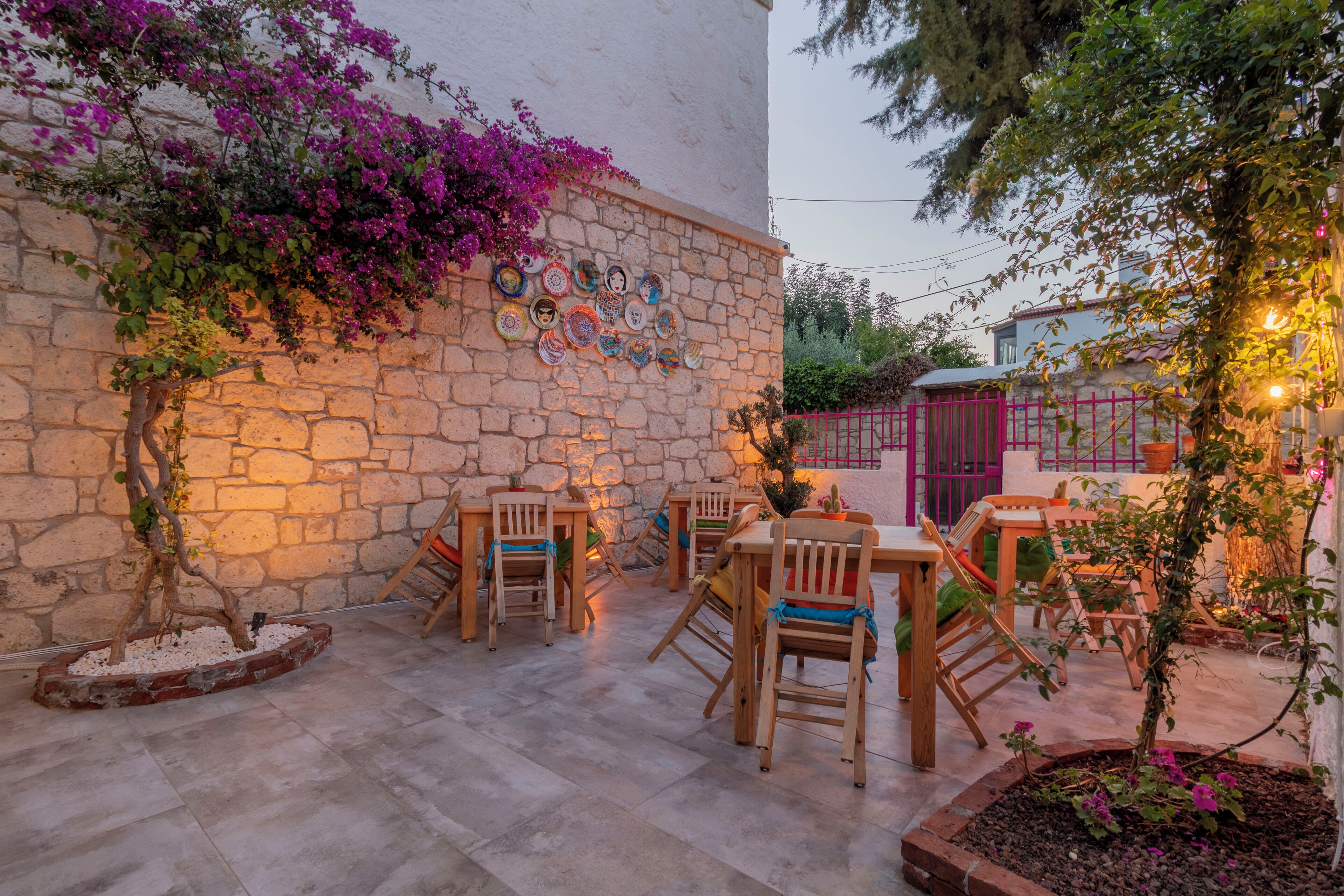An outdoor patio with stone walls, wooden furniture, and decorative plates.