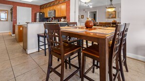 A spacious kitchen with wooden cabinets, a central island, and a dining area with a large wooden table and chairs. - Gorgeous oceanfront vacation rental condo with amazing views and pool (North Myrtle Beach)
