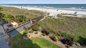 A beach view from a deck with a wooden railing, overlooking a sandy beach with people and a clear sky. - Gorgeous oceanfront vacation rental condo with amazing views and pool (North Myrtle Beach)