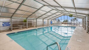 An indoor pool with a glass ceiling, clear signage indicating shallow water and no diving allowed, and a view of the outdoors. - Gorgeous oceanfront vacation rental condo with amazing views and pool (North Myrtle Beach)