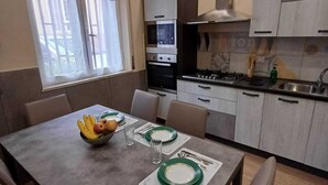 Una cocina moderna con comedor. Incluye estufa, horno y ventana con cortinas.