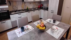 Una cocina moderna con armarios grises, una estufa a gas y una mesa de comedor con individuales y un cuenco de fruta.