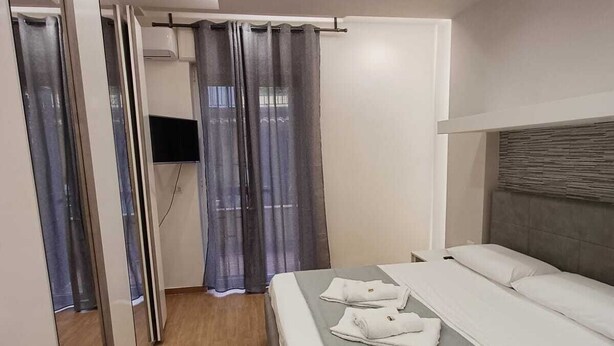 Una habitación de hotel moderna con una cama grande, un televisor de pantalla plana y un espejo.