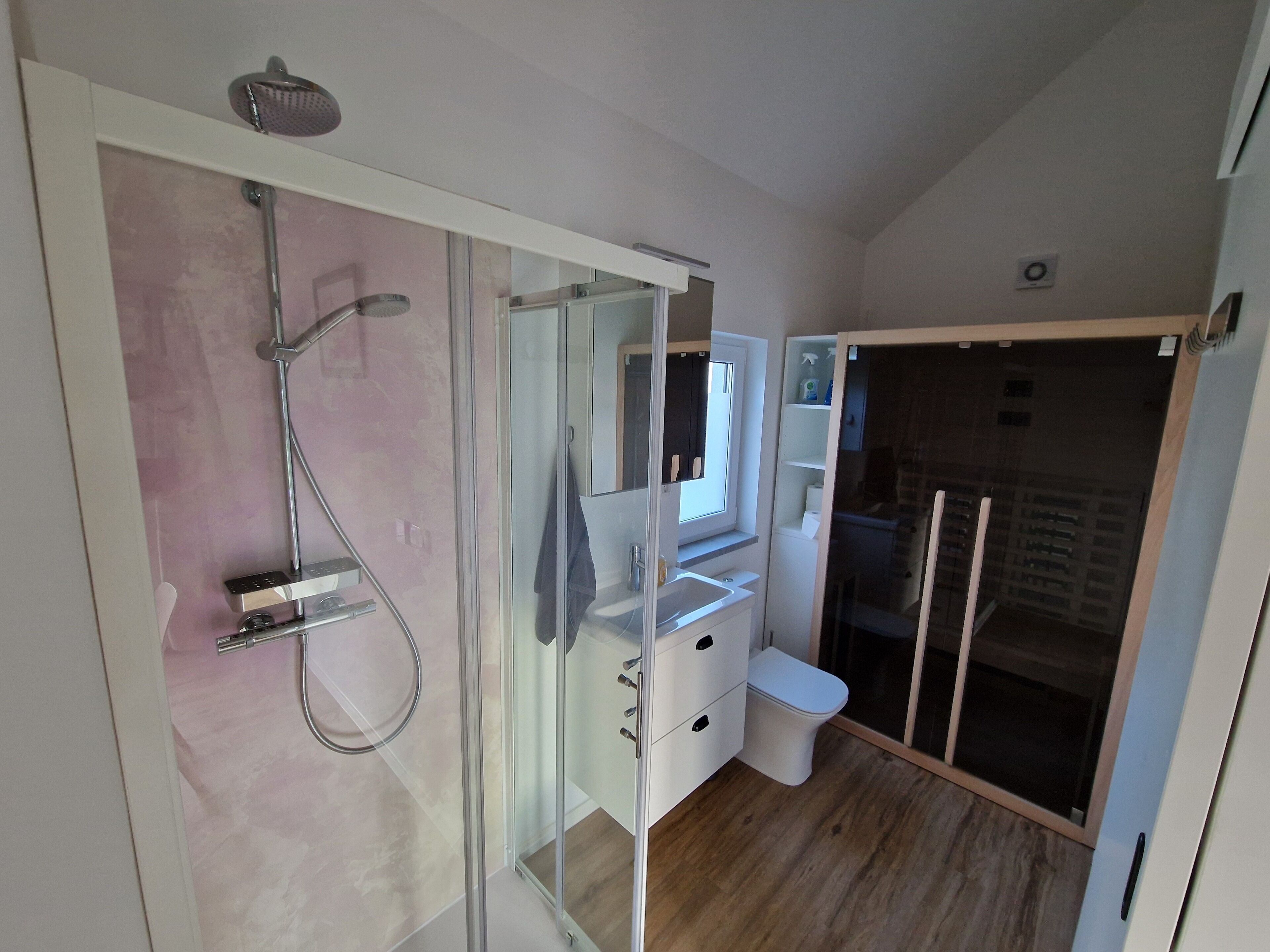 A modern bathroom with a glass shower enclosure, a toilet, and a sink.
