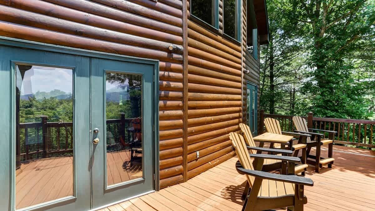 A wooden cabin with a deck, sliding glass doors, and outdoor seating.