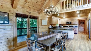 A wooden cabin interior with a dining area, kitchen, and a balcony with a wooden railing. - Scenic Mountain Cabin w/ Hot Tub & Fire Pit (Blue Ridge)