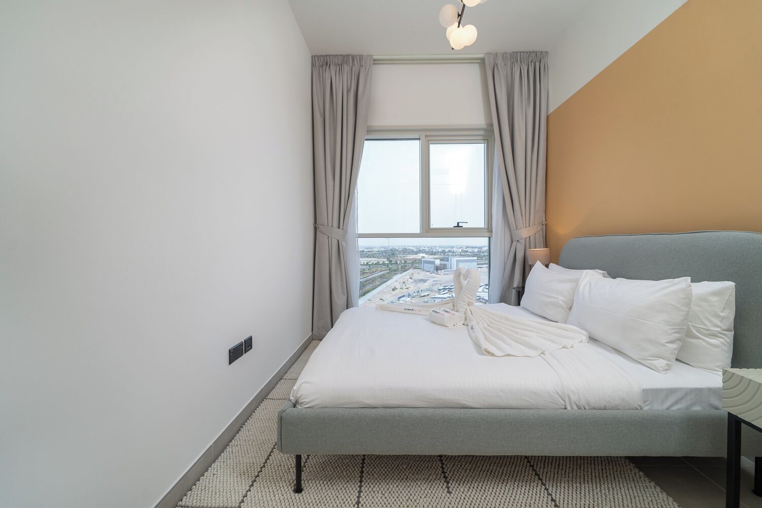 A modern hotel room with a large bed, a view of the city, and a simple, clean design.