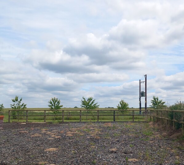 A rural landscape with a gravel path, a wooden fence, and a utility pole in the distance. - 2 Bed Cambridge Lodge (Market Drayton)