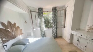 Une chambre à coucher comprenant un lit, une fenêtre avec des rideaux, une armoire et un élément décoratif fixé au mur.