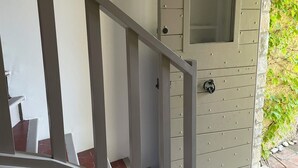 Un escalier menant à une porte au design original, un miroir fixé au mur et un motif décoratif en forme de soleil rayonnant.