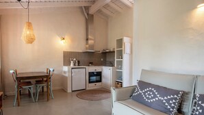 A compact living space with a dining area, kitchenette, and a sofa with patterned cushions. - Nômade Melides Eco Lodge (Grandola)