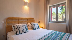 A bed with a woven headboard, white bedding, and a striped blanket. - Nômade Melides Eco Lodge (Grandola)