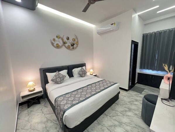 Une chambre moderne avec un grand lit, des lampes de chevet, un ventilateur de plafond et un appareil de climatisation.