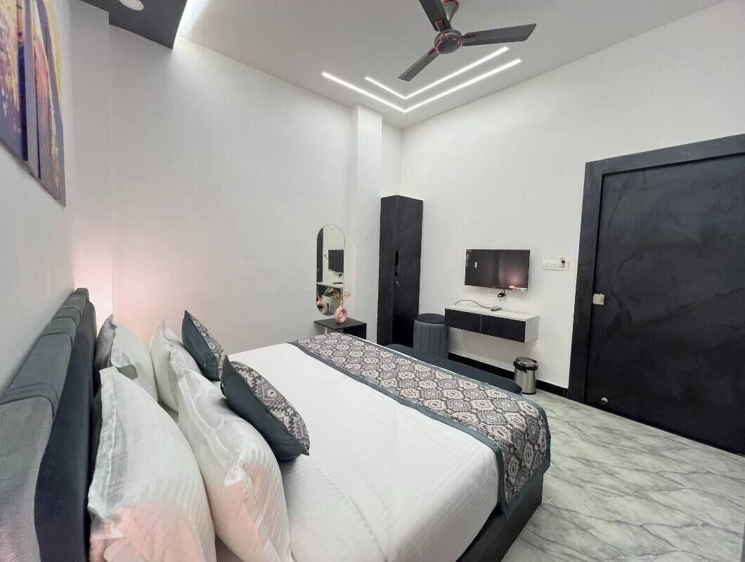 A modern bedroom with a bed, bedside table, wardrobe, and a TV.