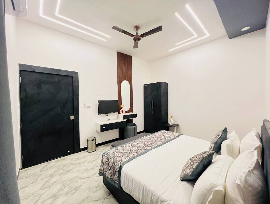 Una camera da letto moderna con un letto grande, una toeletta con uno specchio, una ventola a soffitto e una porta nera.