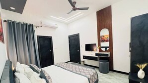 Ein modernes Hotelzimmer mit einem Bett, einem Schreibtisch, einem Fernseher und einem Deckenventilator.