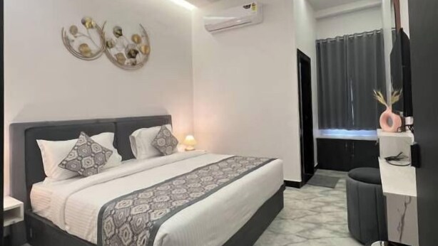 Ein modernes Schlafzimmer mit Bett, Nachttischen, Klimaanlage, Deckenventilator und einem Badezimmer mit Dusche und Toilette.