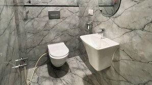 Ein Badezimmer mit Marmorwand, Toilette, Waschbecken und Spiegel.