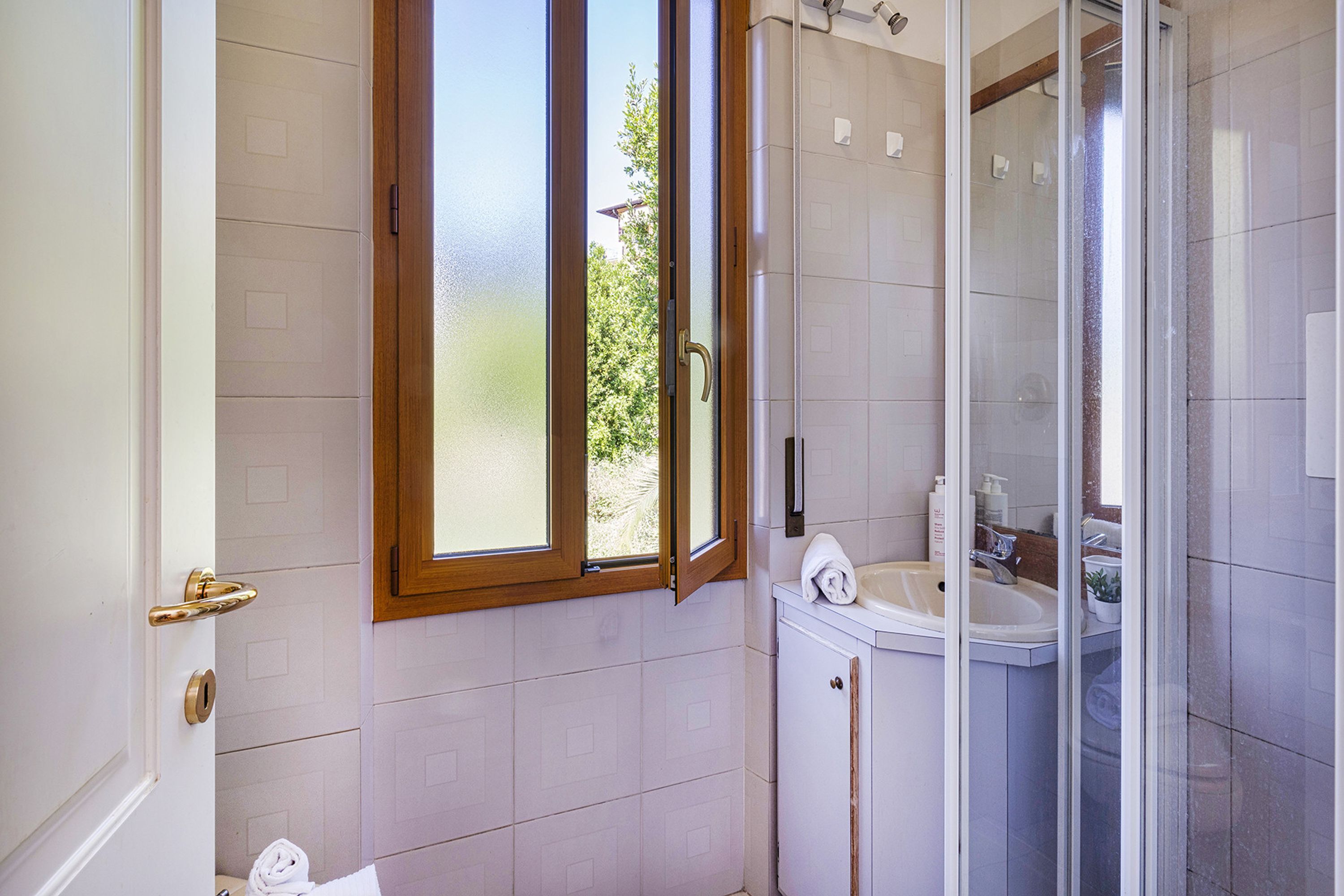 A bathroom with a shower, a sink, and a window.