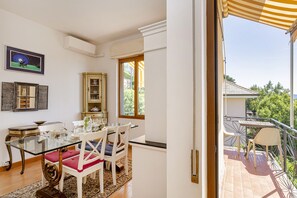 A dining area with a glass table, white chairs, and a view of the outdoors. - Giovo Sea View Balcony by Wonderful Italy (Santa Margherita Ligure)