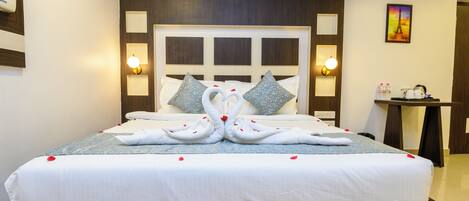 A neatly made bed with a decorative swan design made from towels, a headboard with built-in lighting, and a small table with toiletries.