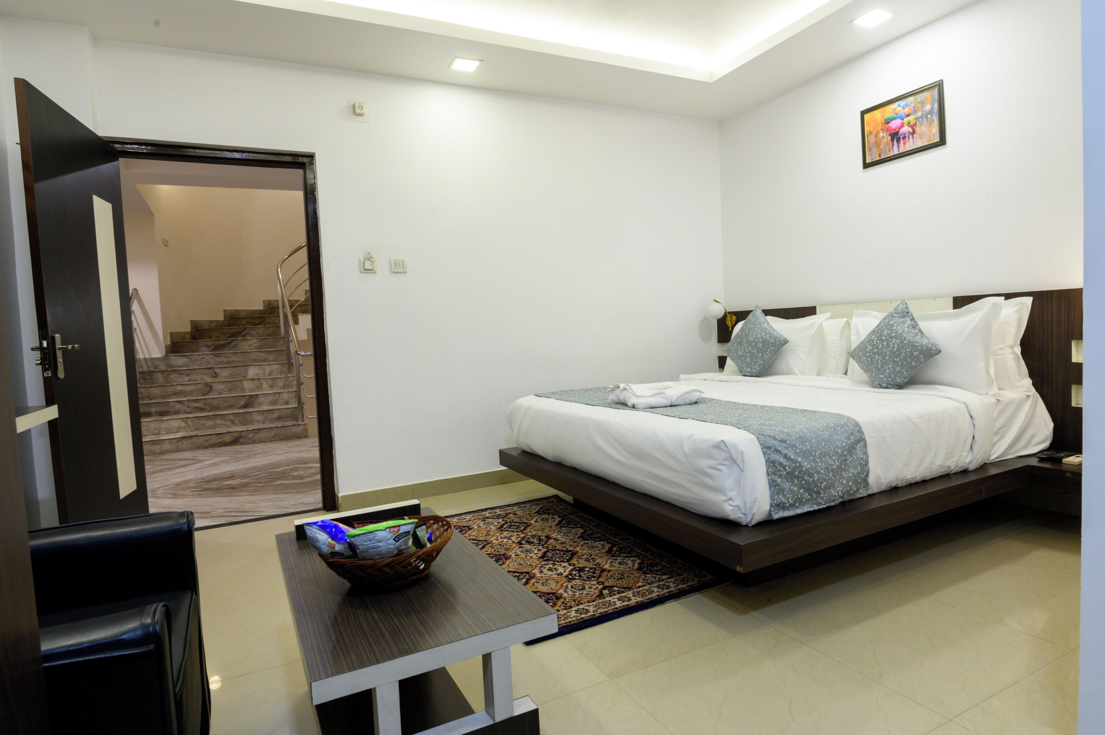 A modern bedroom with a bed, a desk, and a chair. There is a staircase leading to another room.