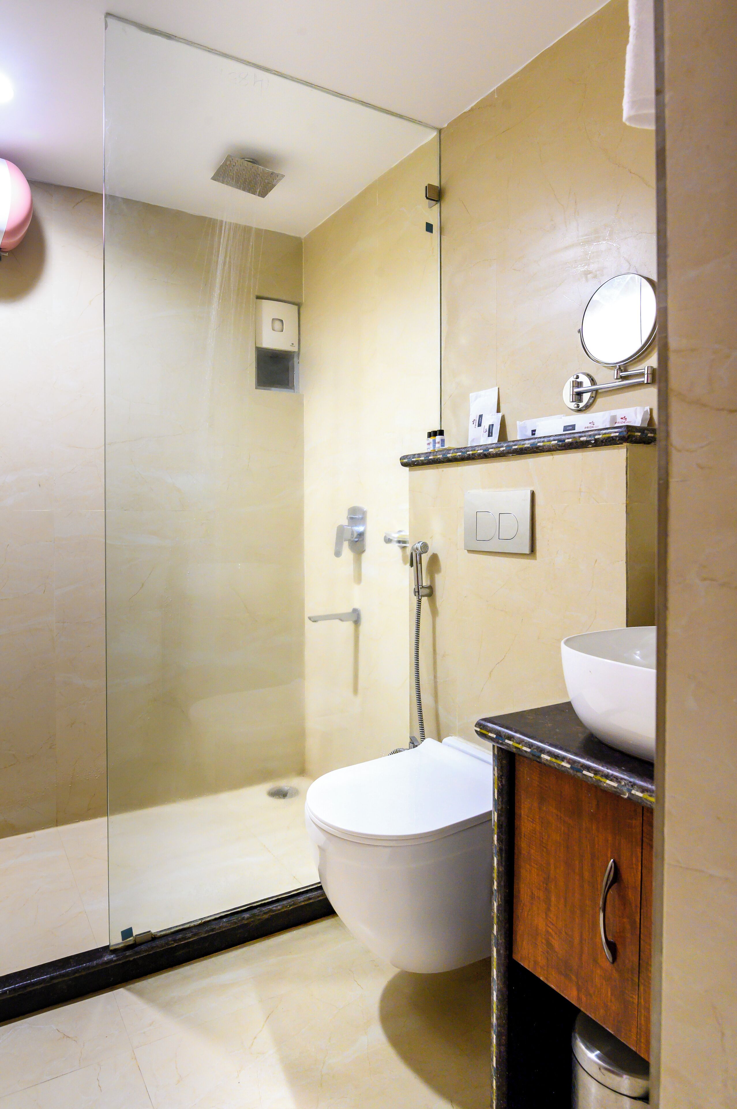 A bathroom with a glass-enclosed shower, a toilet, and a sink with a mirror above it.