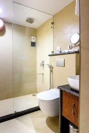 A bathroom with a glass-enclosed shower, a toilet, and a sink with a mirror above it.