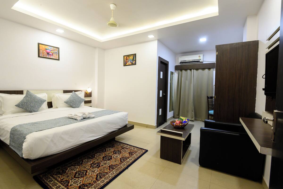 A modern hotel room with a large bed, a desk, and a TV.