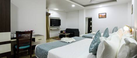 A hotel room with two beds, a desk, a chair, a television, and a small table.